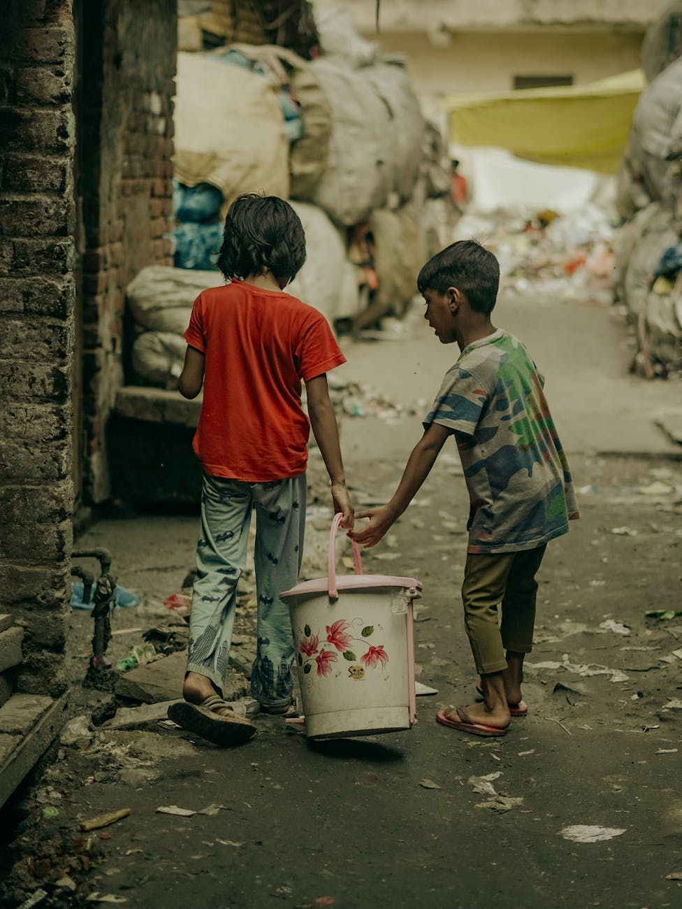 children carrying water bucket in delhi alley